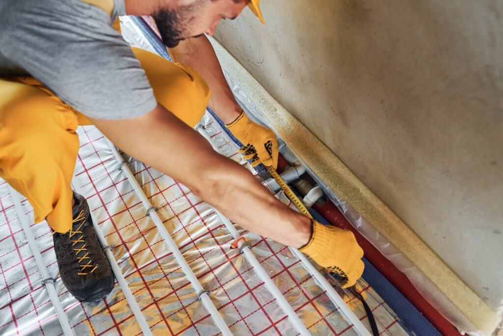 Worker in yellow colored uniform installing underfloor heating system