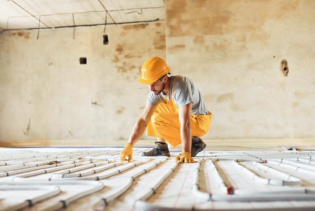 Worker in yellow colored uniform installing underfloor heating system